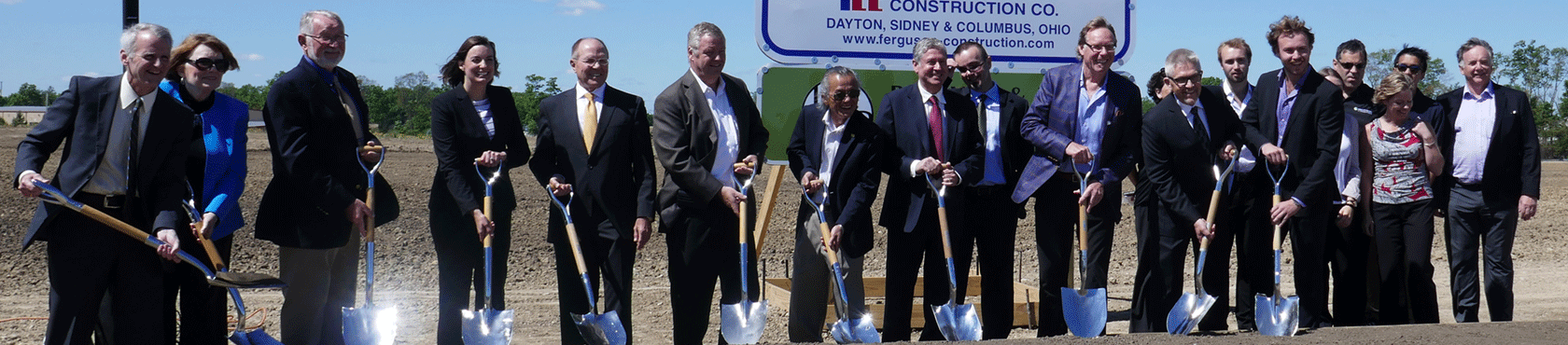 Group posing with shovels at future facility site