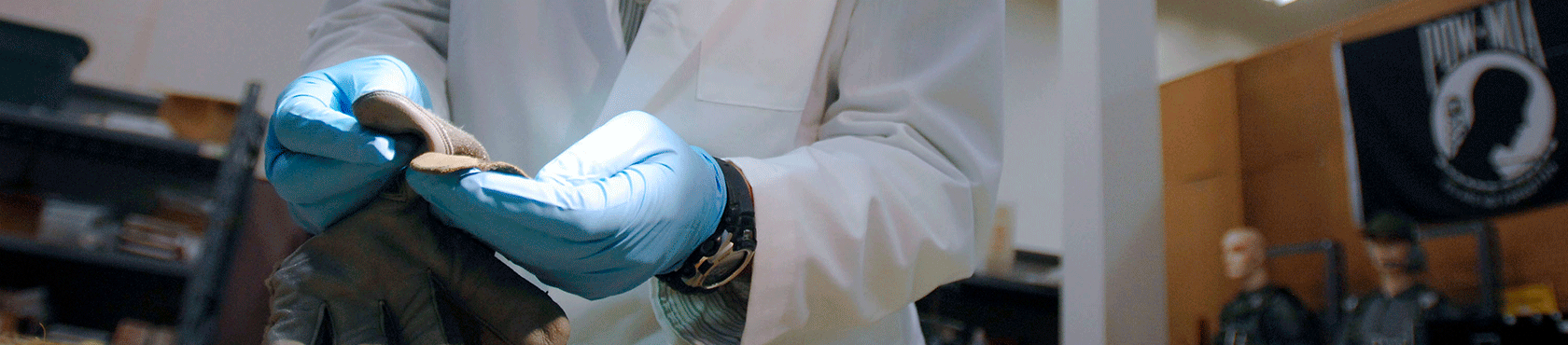 Blue gloves holding gray glove under light